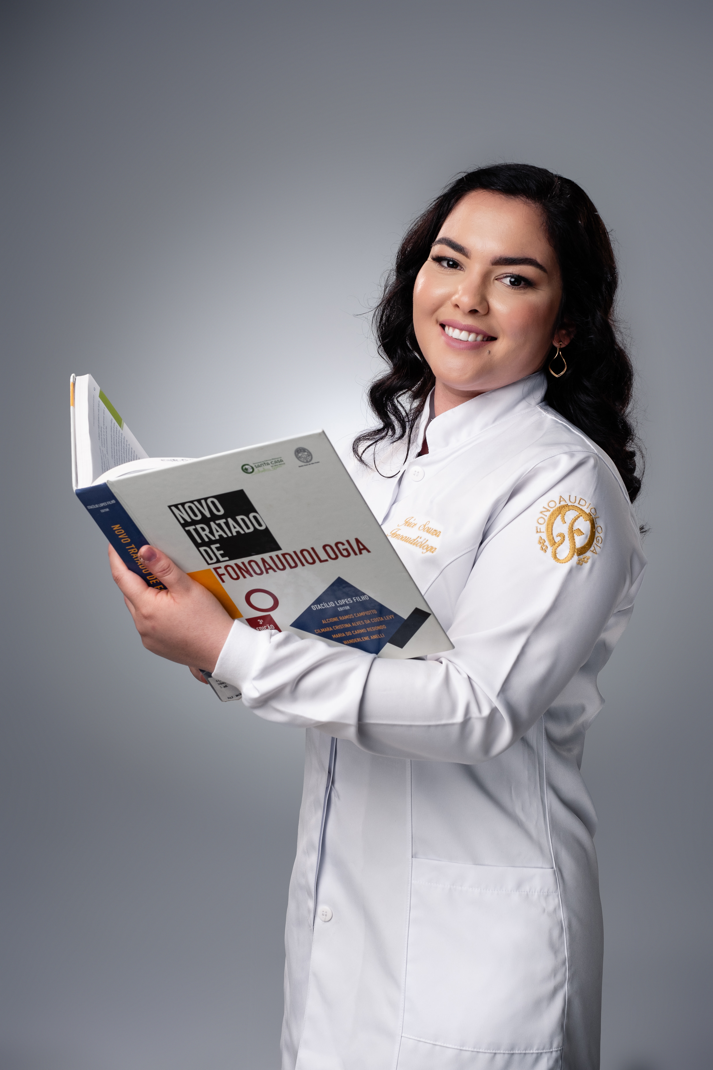 Fonoaudióloga sorrindo com livro de fonoaudiologia